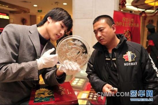 12月21日，工作人員向顧客介紹一款5公斤重的壬辰賀歲紀(jì)念大銀章，其正面的“金龍降喜”圖案，寓意對(duì)龍年萬事亨通的美好祝福。
