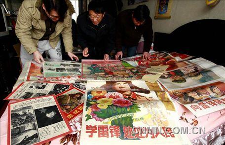 3月1日，房冠龍（中）在家中整理關(guān)于雷鋒的宣傳海報。