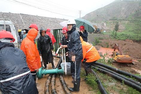 圖一為中州鋁業(yè)保障中心員工冒雨在現(xiàn)場搬運潛水泵設(shè)備，以應(yīng)對未來幾天更加嚴峻的汛情。